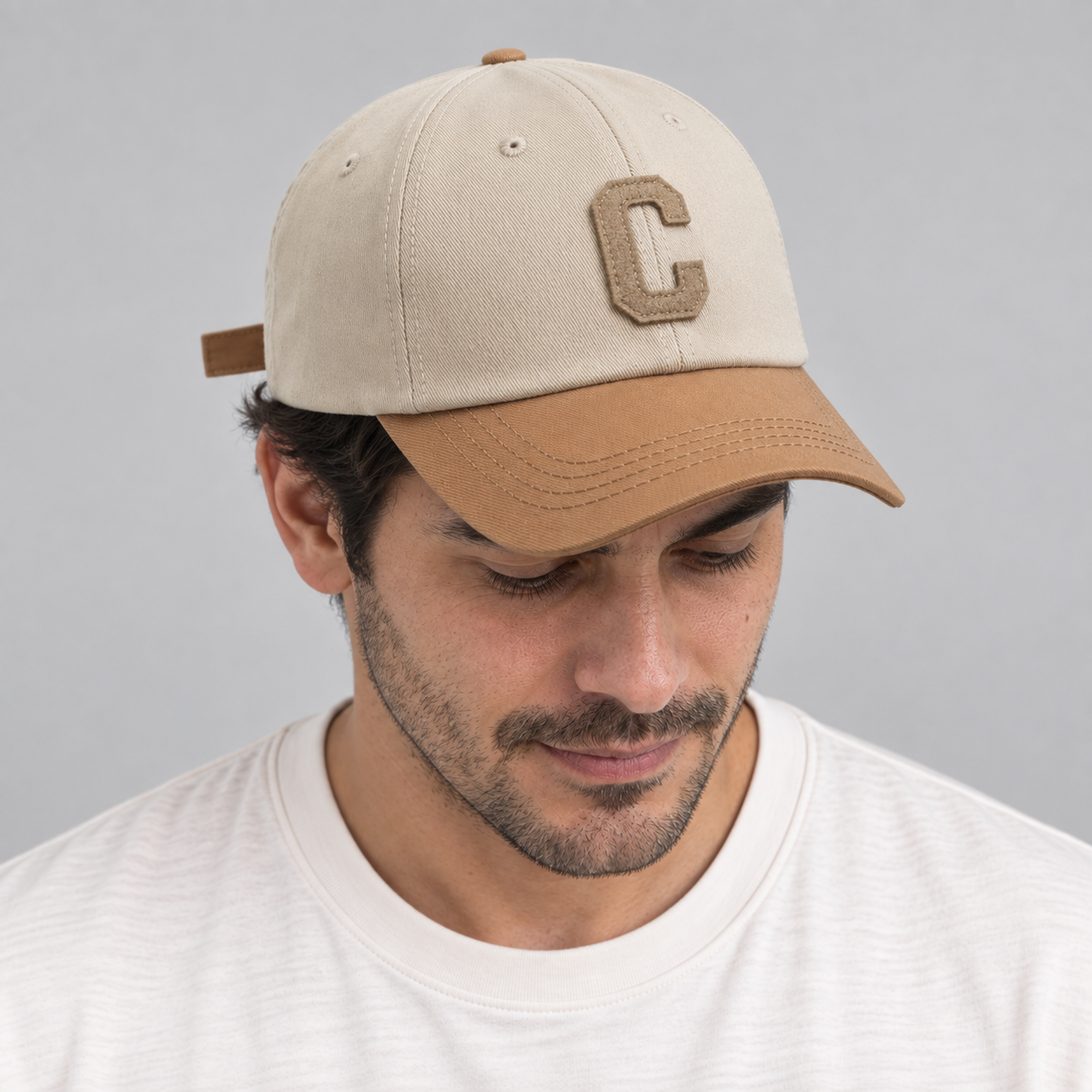 Gorro Bicolor C beige, hombre mirando hacia abajo mostrando la visera camello