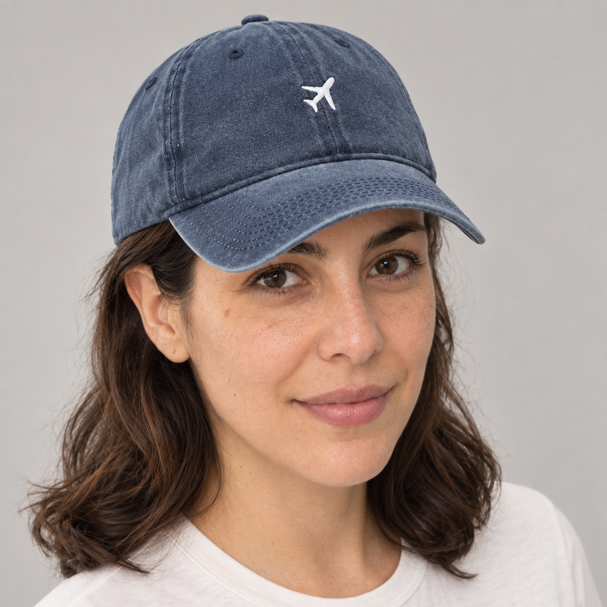 Detalle del bordado de avión y visera azul en modelo mujer